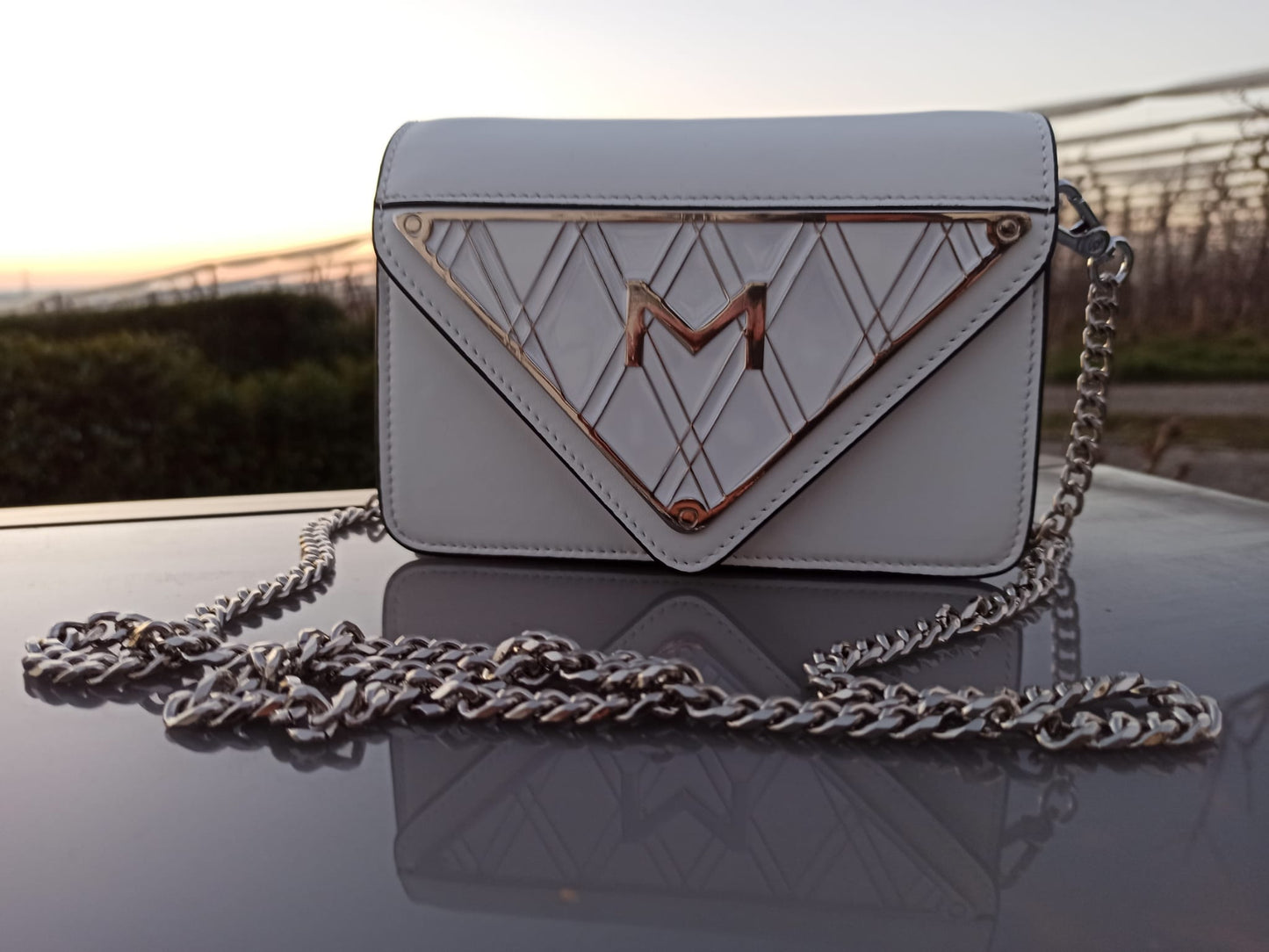Frontansicht der weißen Handtasche aus glänzendem Leder mit emailliertem Metall-Logo