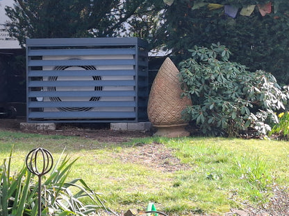 Wärmepumpen-Verkleidung XL AIR für Bosch Compress 6800i AW in einer Gartenlandschaft unter Nadelbäumen.