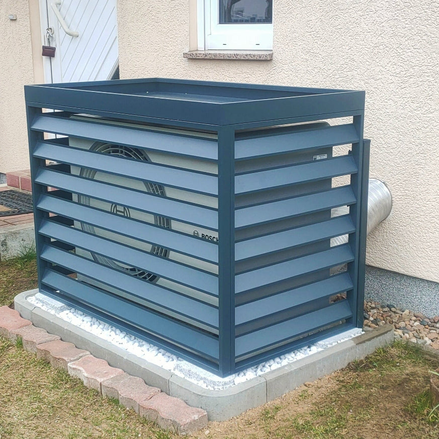 Bosch Compress 5800i AW Luft-Wasser-Wärmepumpe mit einer Wärmepumpen Abdeckung XL AIR vor der Fassade eines modernen Wohnhauses installiert