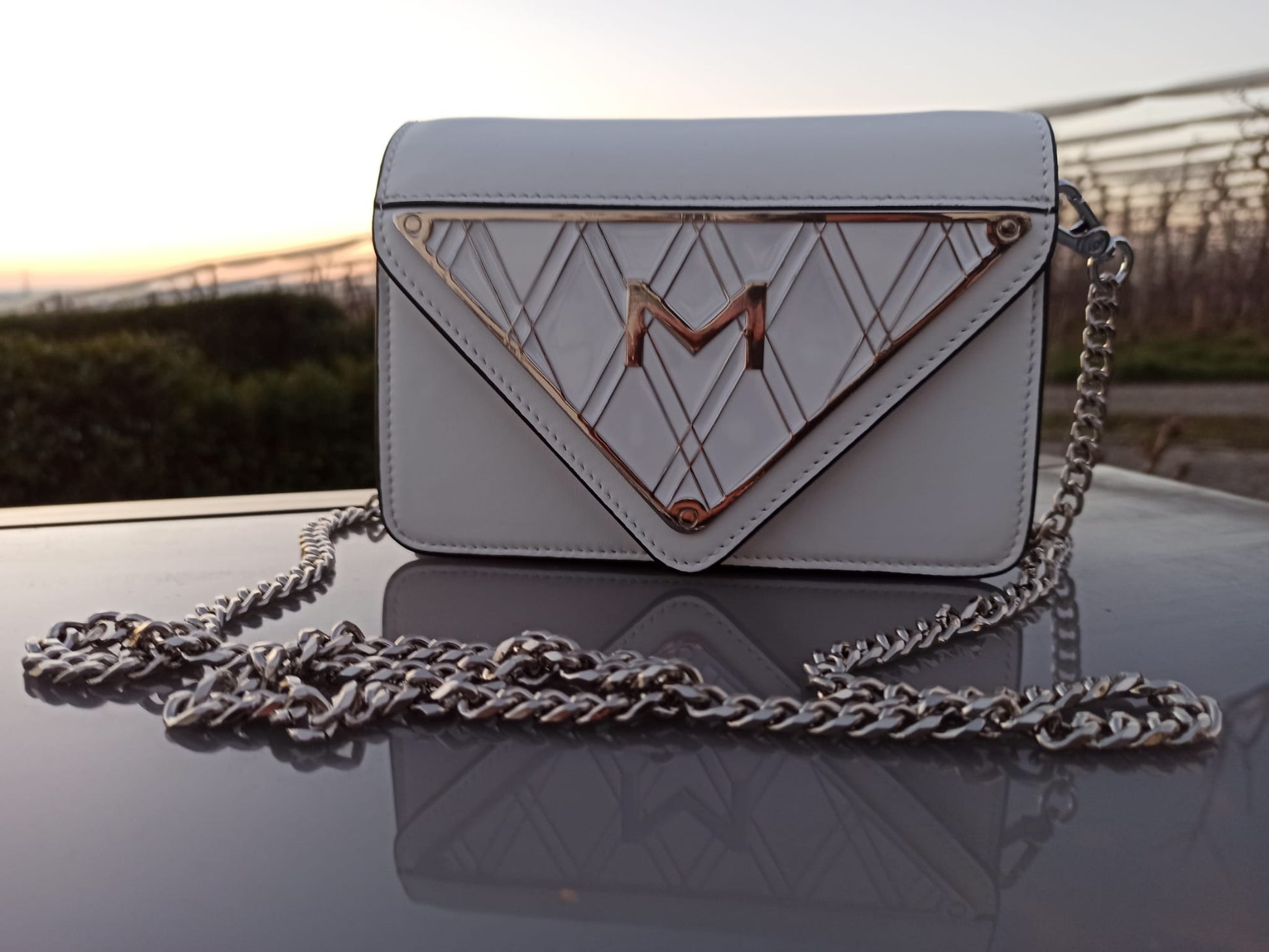 Frontansicht der weißen Handtasche aus glänzendem Leder mit emailliertem Metall-Logo